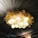 A ceiling adorned with a decorative arrangement featuring soft glowing spherical lights and a wreath-like structure with leaf-shaped elements. The draped fabric ceiling panels create a luxurious and elegant atmosphere.