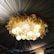 A ceiling adorned with a decorative arrangement featuring soft glowing spherical lights and a wreath-like structure with leaf-shaped elements. The draped fabric ceiling panels create a luxurious and elegant atmosphere.
