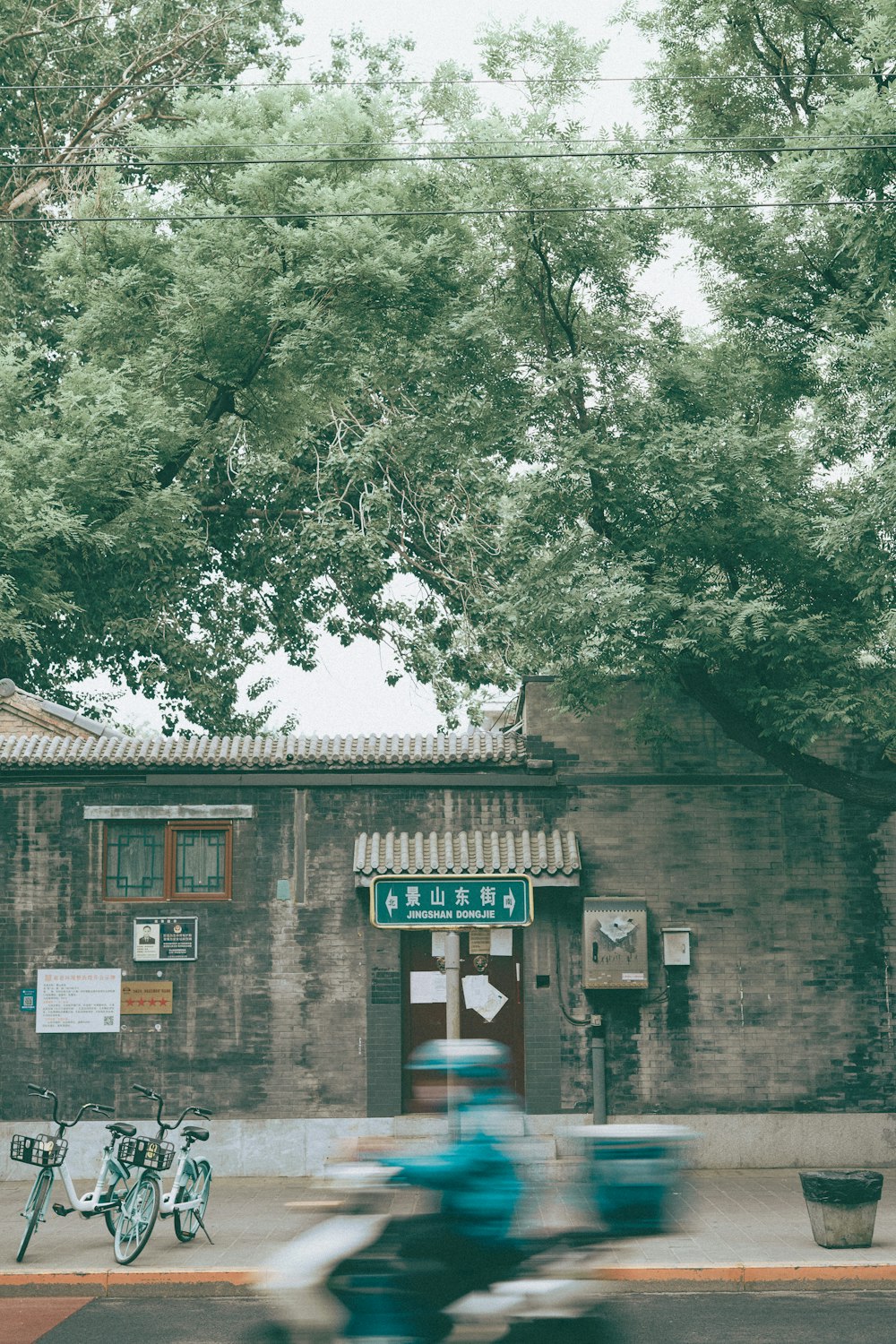 a motorcyclist rides past a building with a sign on it