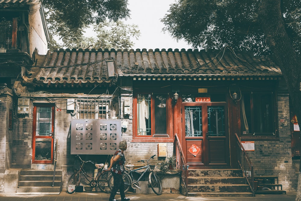 man in black shirt riding bicycle near brown wooden house during daytime