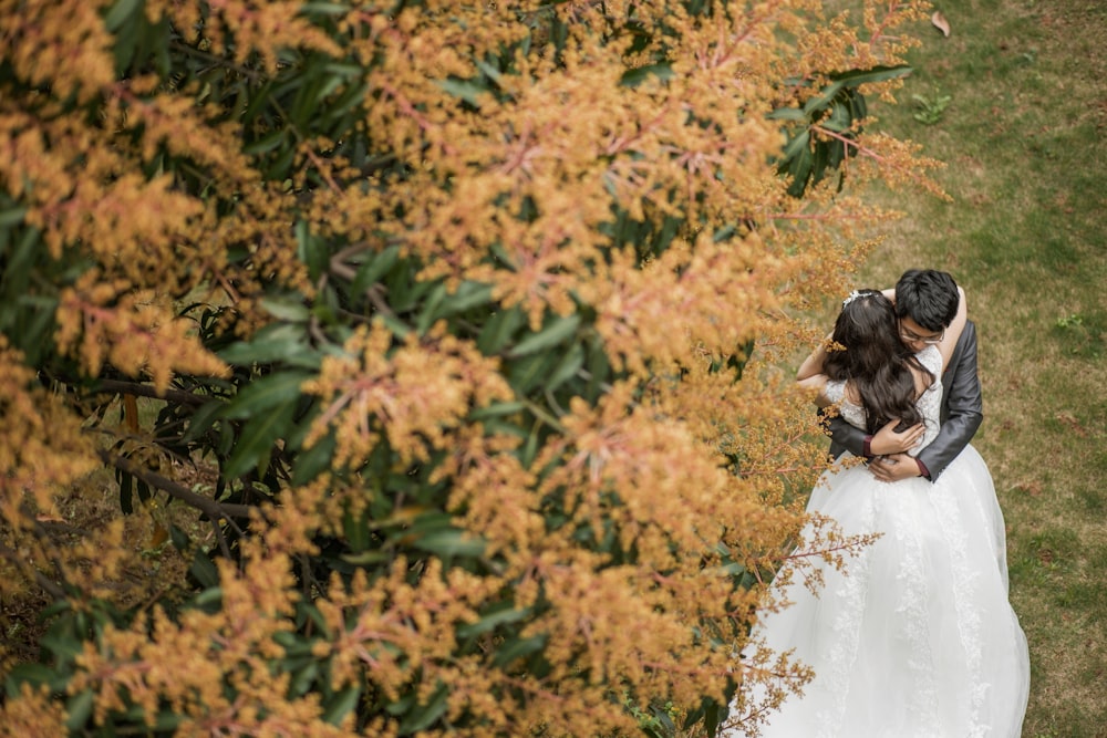 woman in white wedding dress standing near brown leaves during daytime