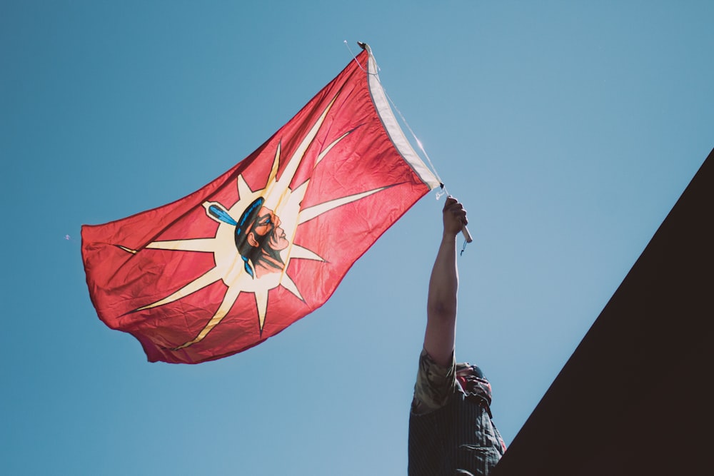 person in black shirt holding red and yellow striped flag