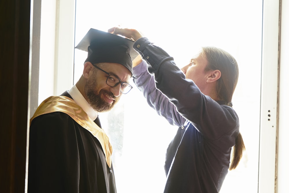 man in white long sleeve shirt holding boy in black academic dress