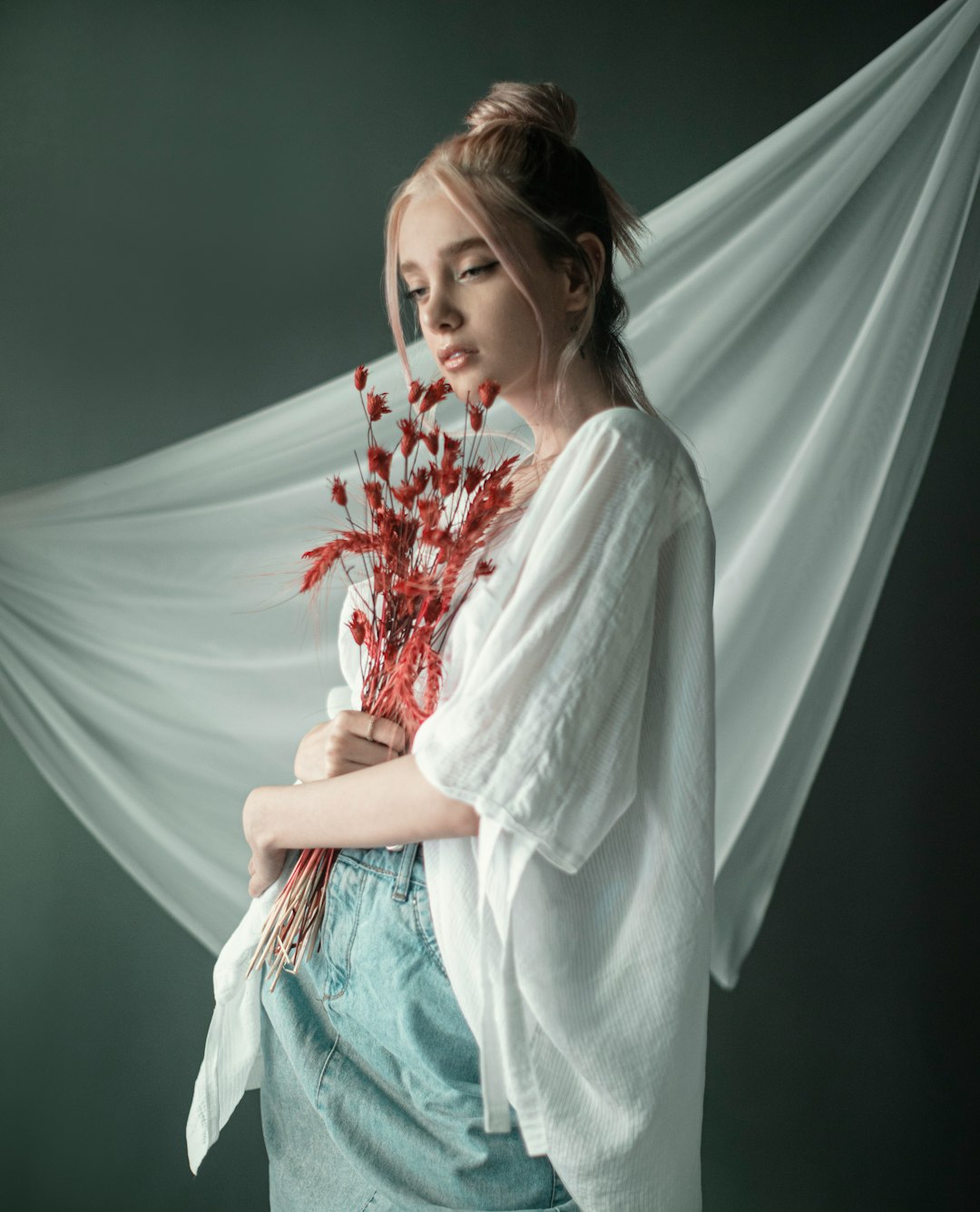 woman in white long sleeve shirt holding red flowers