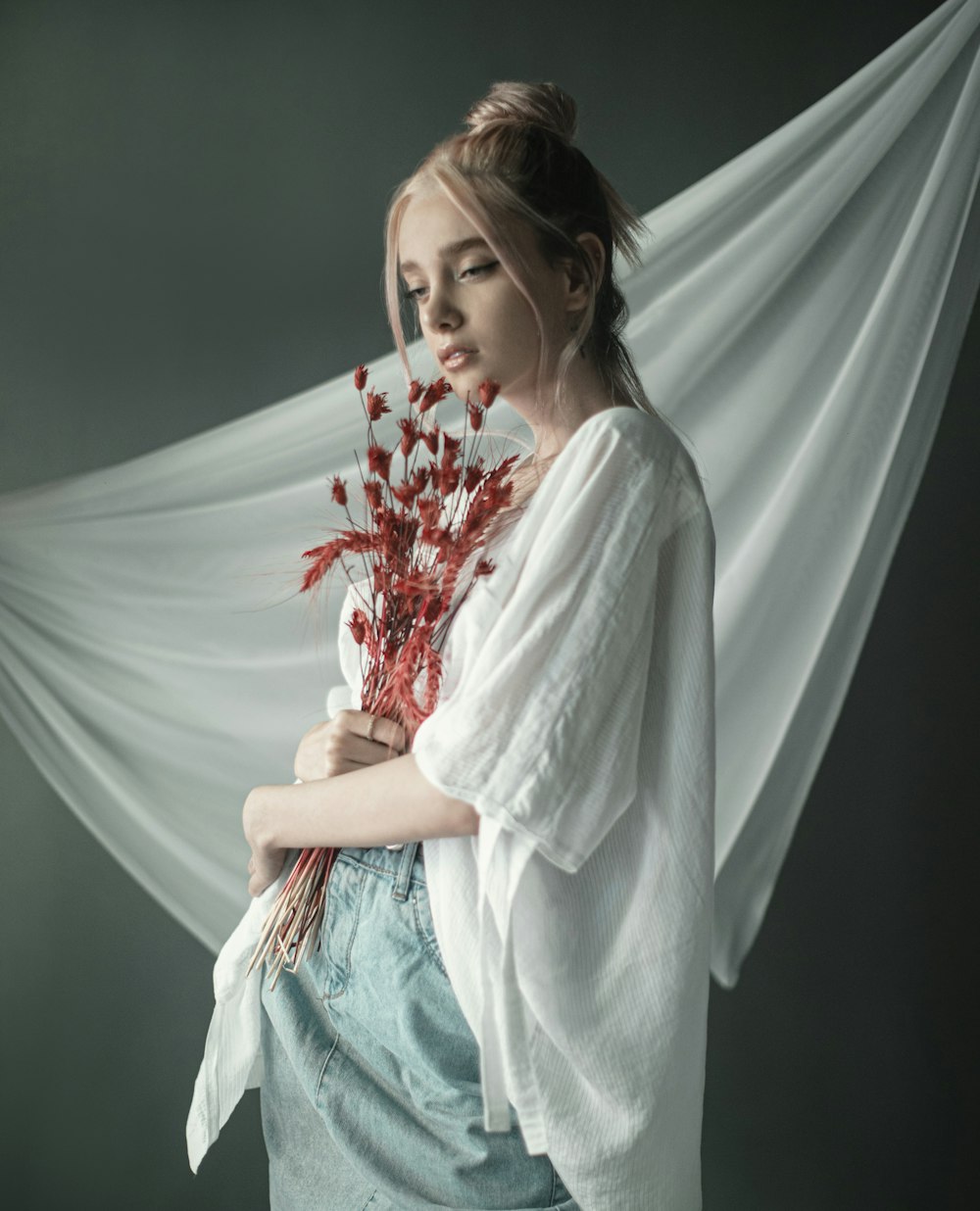 woman in white long sleeve shirt holding red flowers
