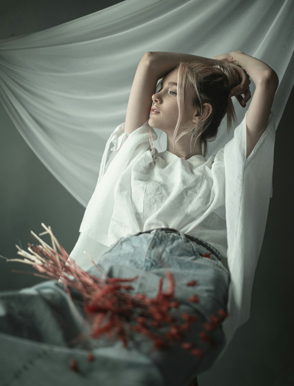 woman in white dress lying on red flowers