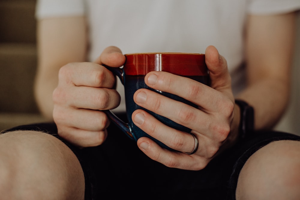 person holding red ceramic mug