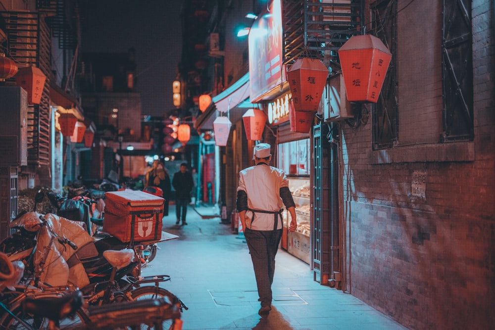 woman in pink coat walking on sidewalk during night time