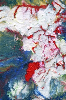 An abstract painting with a blend of colors including red, white, and green. The paint appears to be applied thickly in an impasto style, creating texture and movement across the canvas.