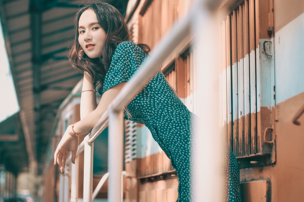 woman in black and white polka dot sleeveless dress standing beside blue metal fence during daytime