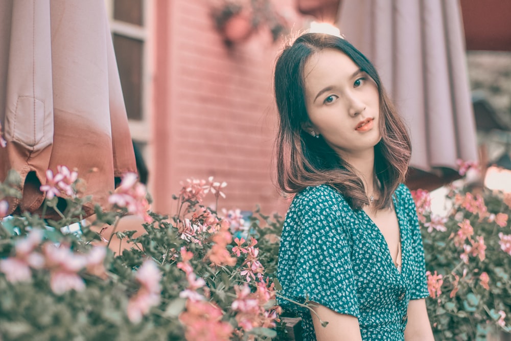 woman in blue and white long sleeve shirt standing beside pink flowers during daytime