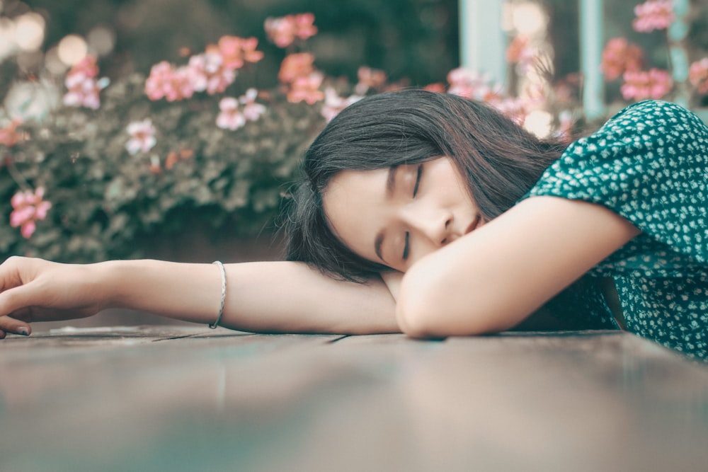 woman in blue and white floral shirt lying on brown wooden floor