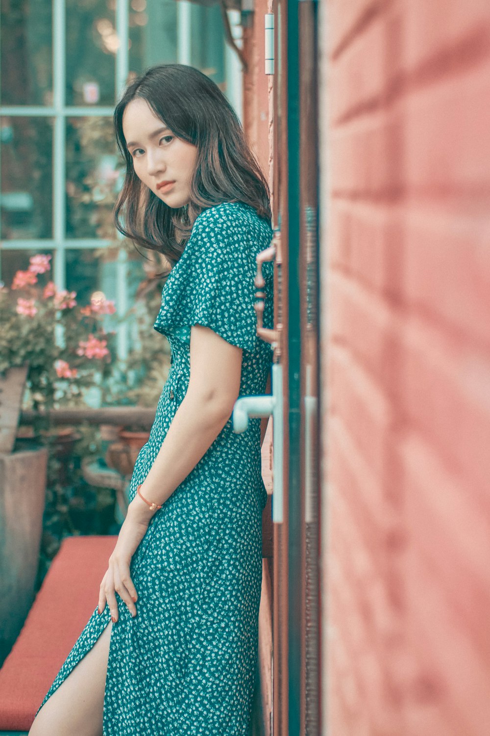 woman in blue and white polka dot dress standing beside red metal railings
