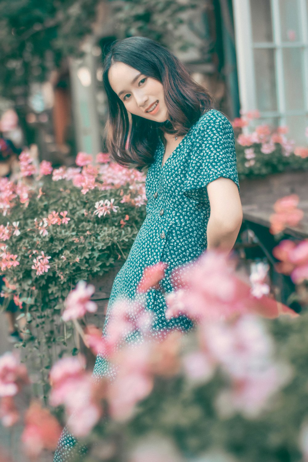 Frau in schwarz-weißem Polka-Dot-Kleid vor rosa Blumen