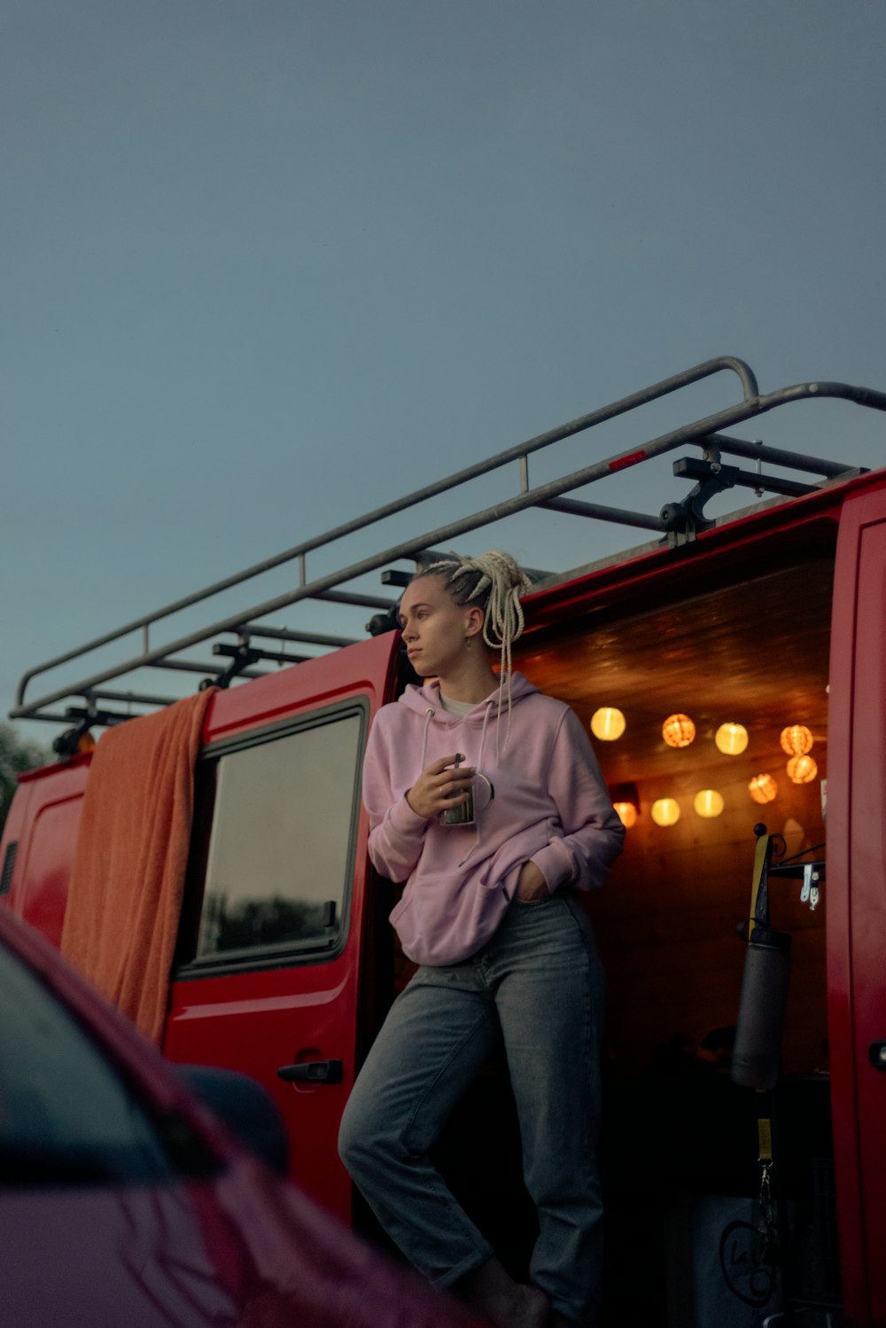 woman in brown jacket and blue denim jeans sitting on red truck during daytime