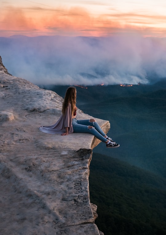 woman in blue denim jeans sitting on rock formation during daytime in Blue Mountains Australia