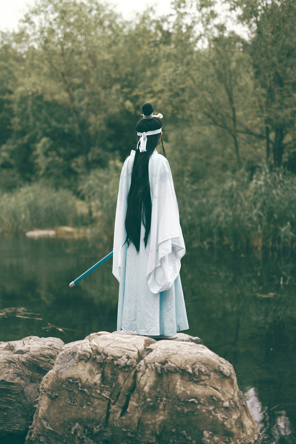 white and black scarf on brown rock near body of water during daytime