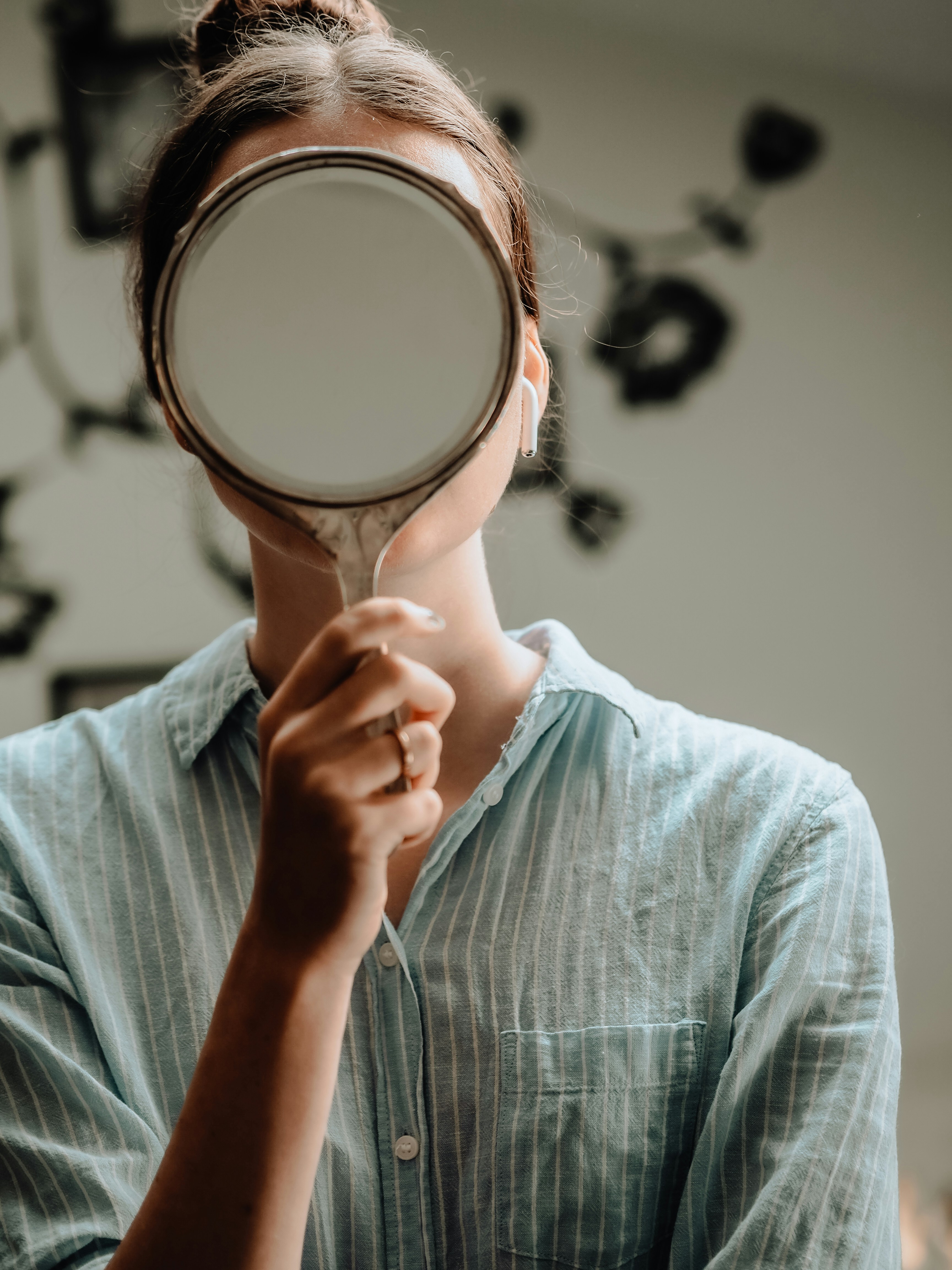 person in blue crew neck shirt holding brown round mirror