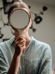person in blue crew neck shirt holding brown round mirror