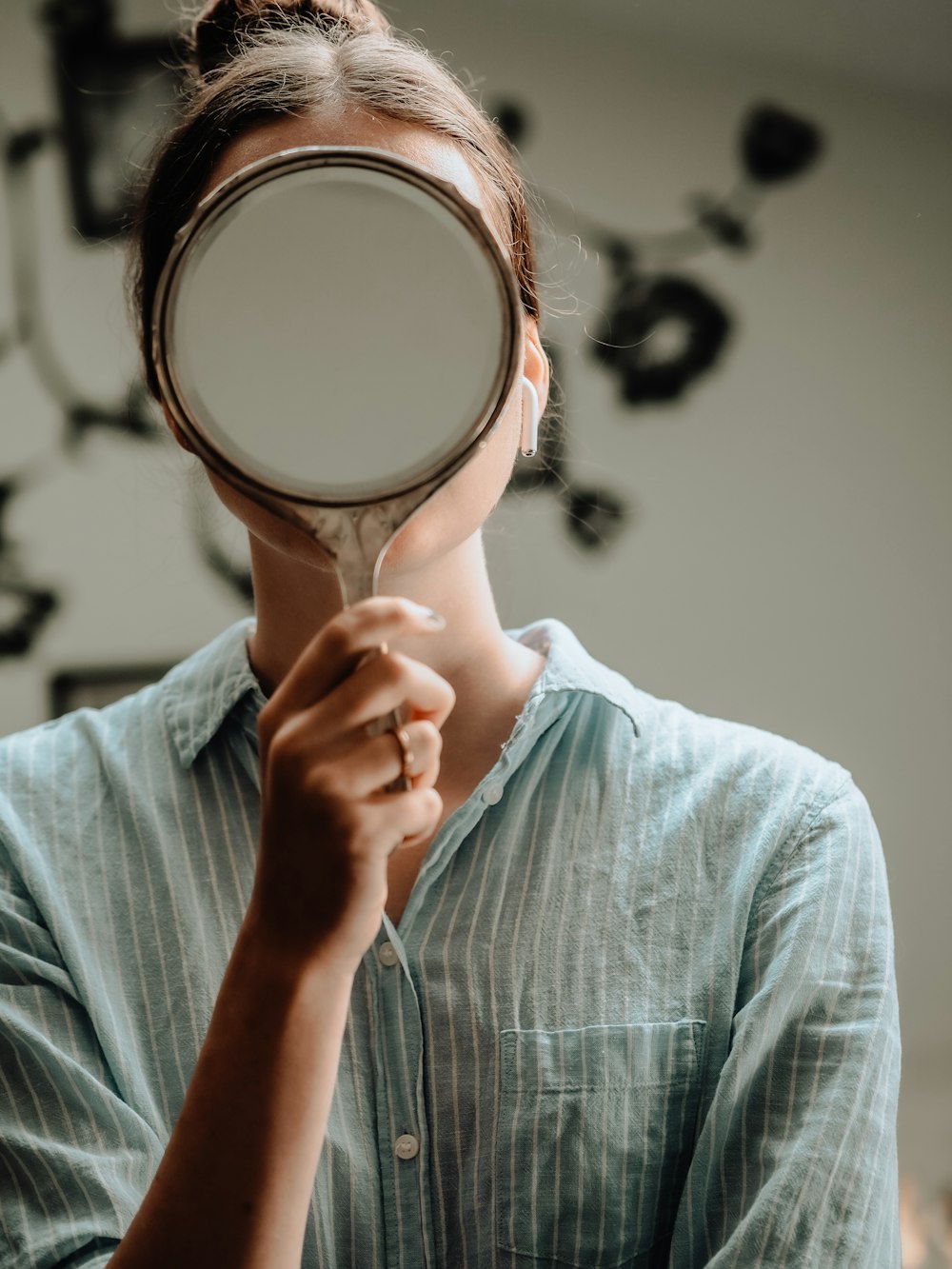 person in blue crew neck shirt holding brown round mirror