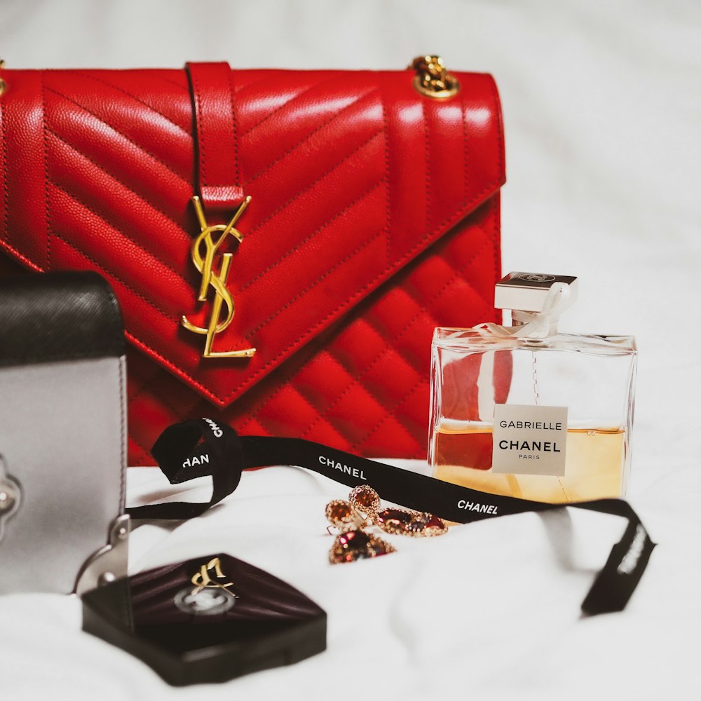 black framed eyeglasses beside red leather handbag