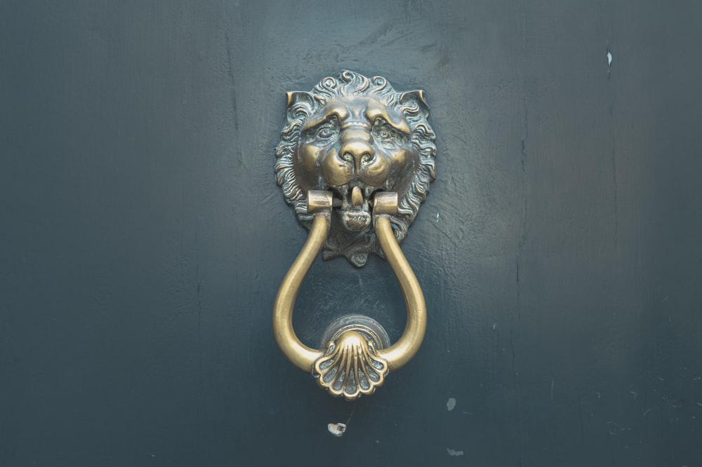 Manija de puerta de león dorado en puerta de madera azul