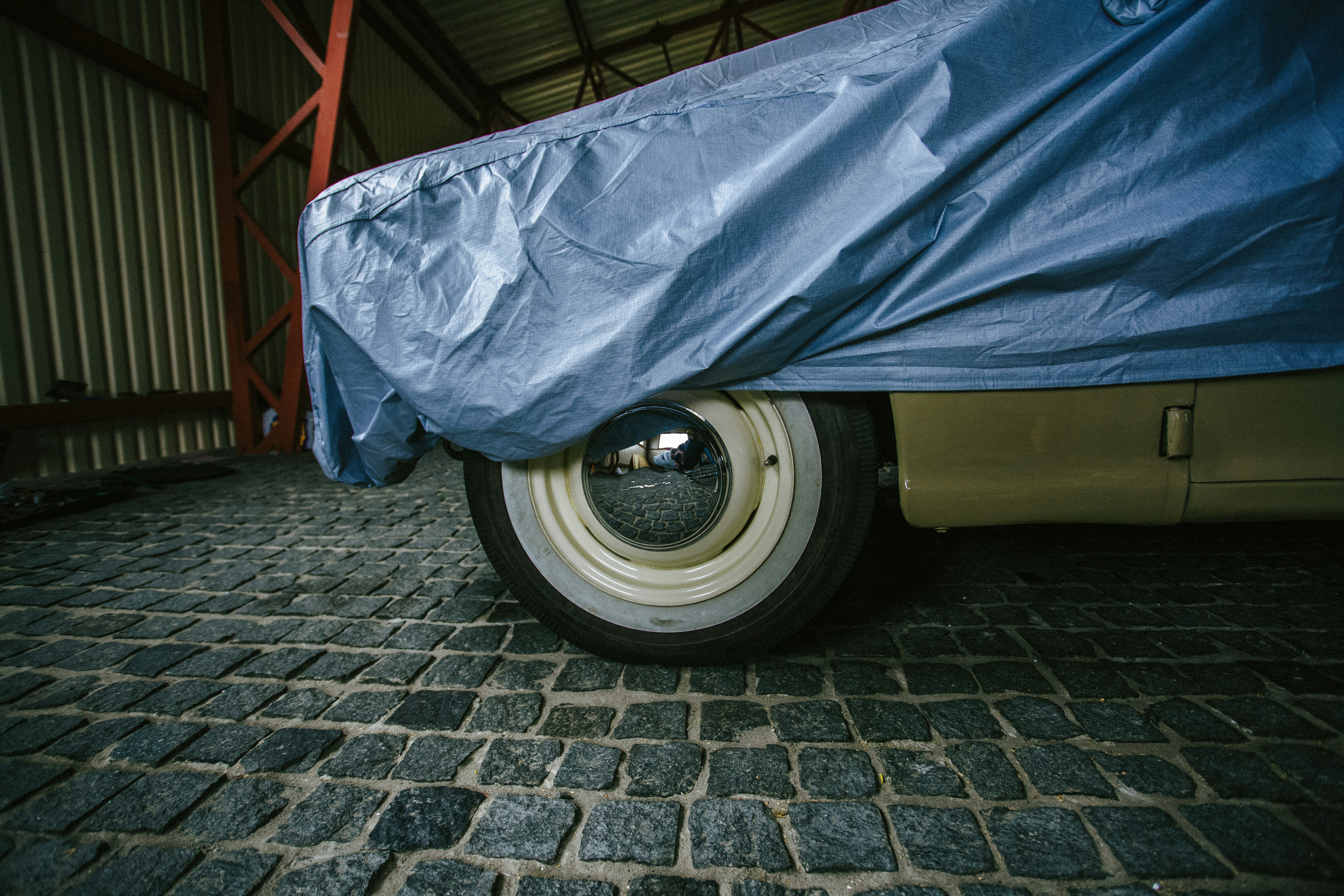 Housse de voiture bleue sur sol en brique grise