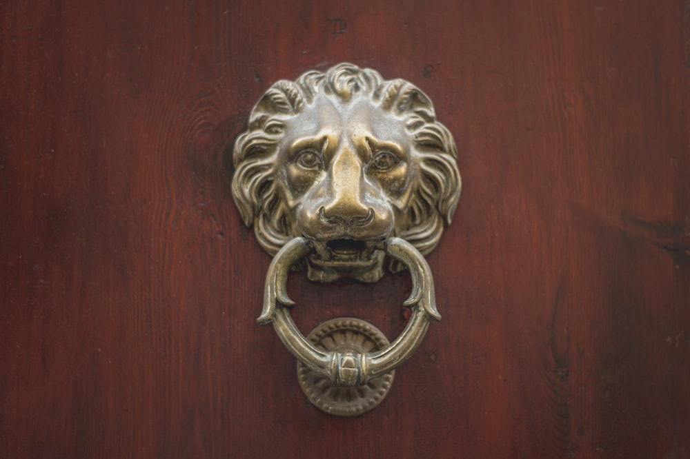 Manija de puerta de león dorado en puerta de madera marrón