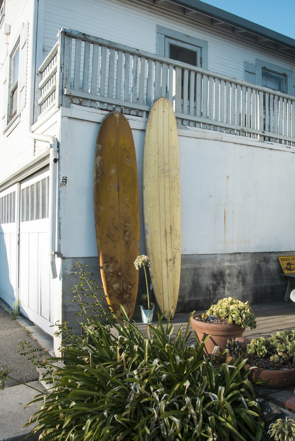 brown surfboard leaning on white wall