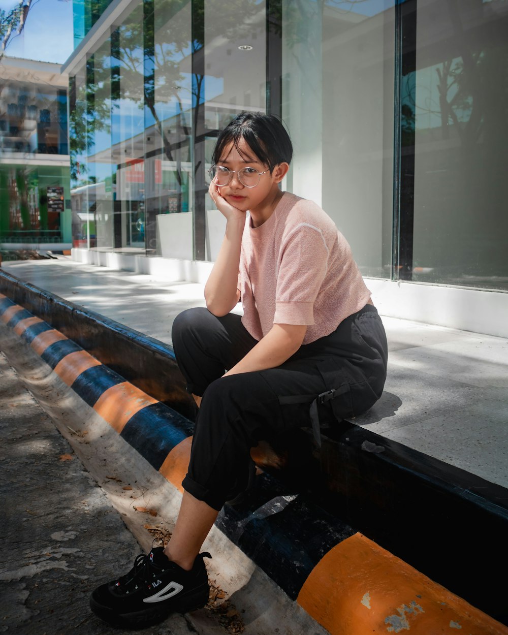 woman in pink crew neck t-shirt and black pants sitting on brown wooden bench