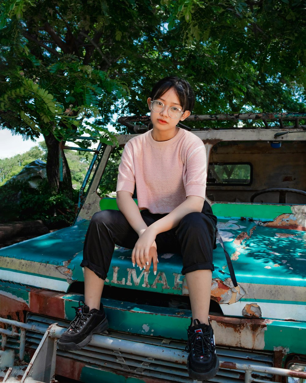 woman in pink crew neck shirt and black pants sitting on brown wooden bench