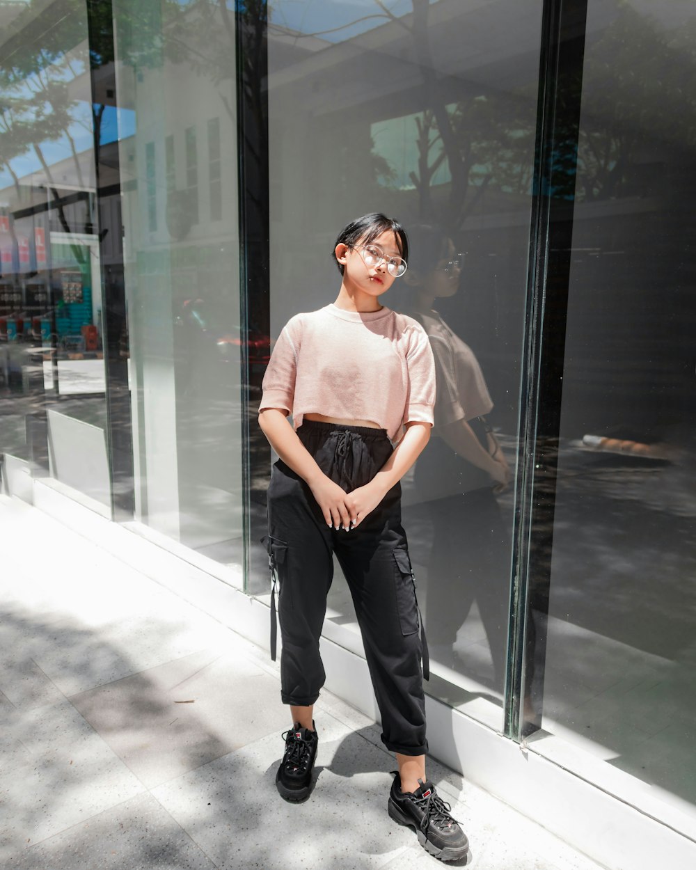 woman in white crew neck t-shirt and black pants standing near glass door