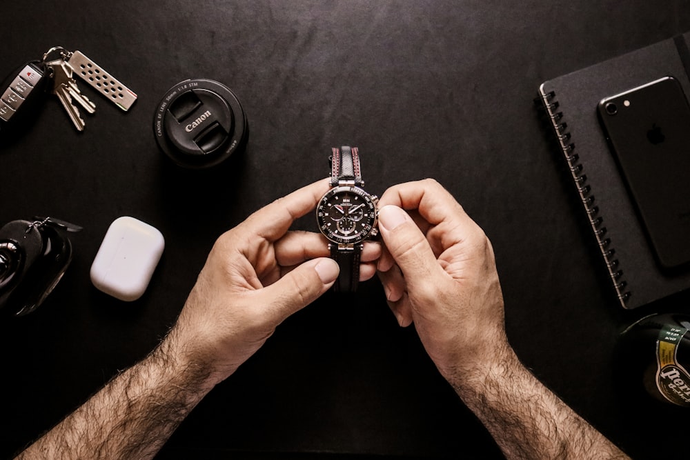 person holding silver and black round analog watch