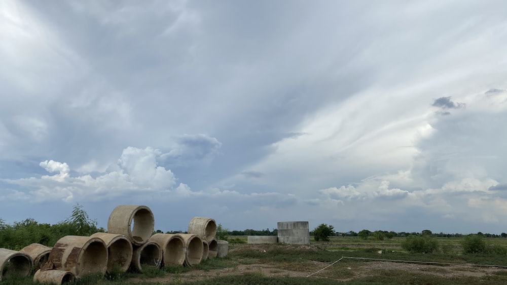 brown wooden barrels on green grass field under white clouds during daytime