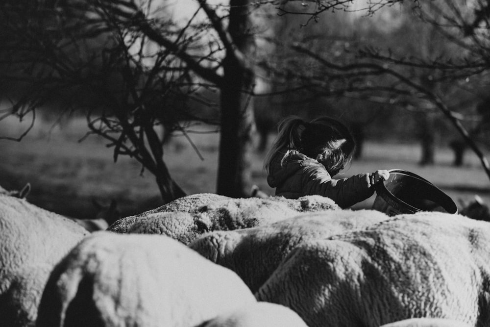 grayscale photo of woman lying on rock