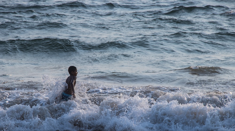 2 boys playing on sea waves during daytime