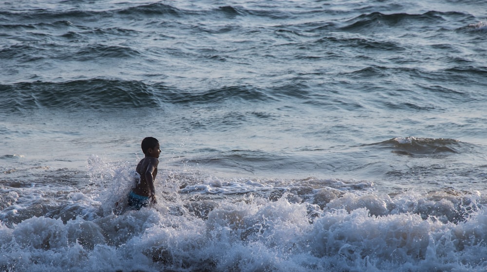 2 niños jugando en las olas del mar durante el día