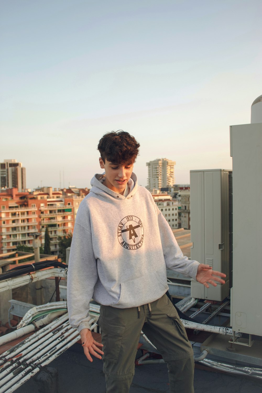 man in gray hoodie standing near building during daytime