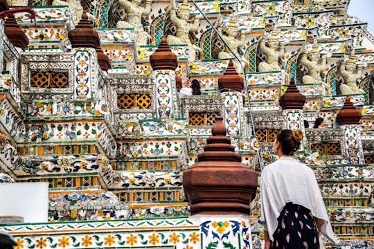 people walking on gold and white temple during daytime in Wat Arun Thailand