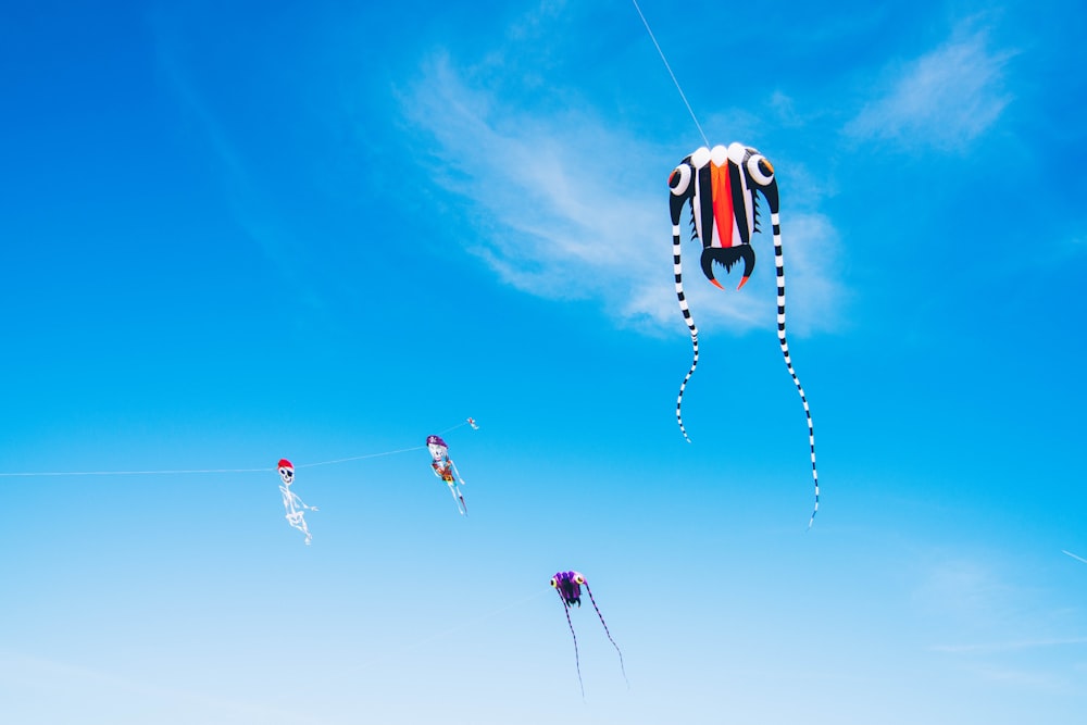 orange and black kite flying under blue sky during daytime
