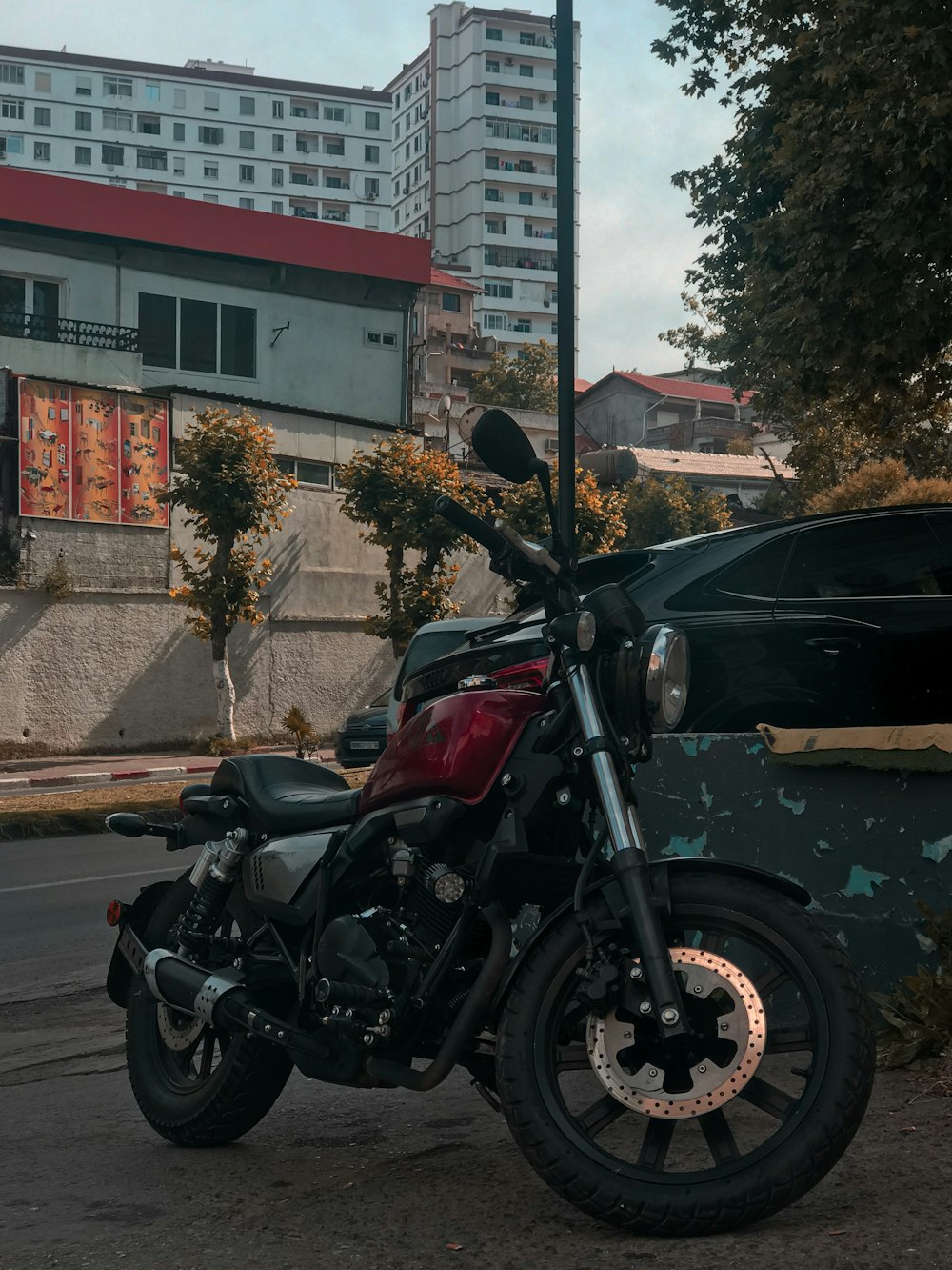 black and red motorcycle parked beside black suv during daytime