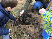 Children planting trees together in a sunny community garden