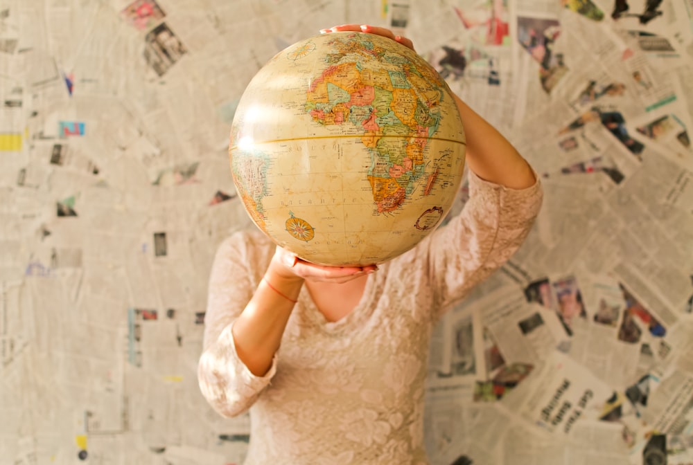 woman in white lace dress holding desk globe