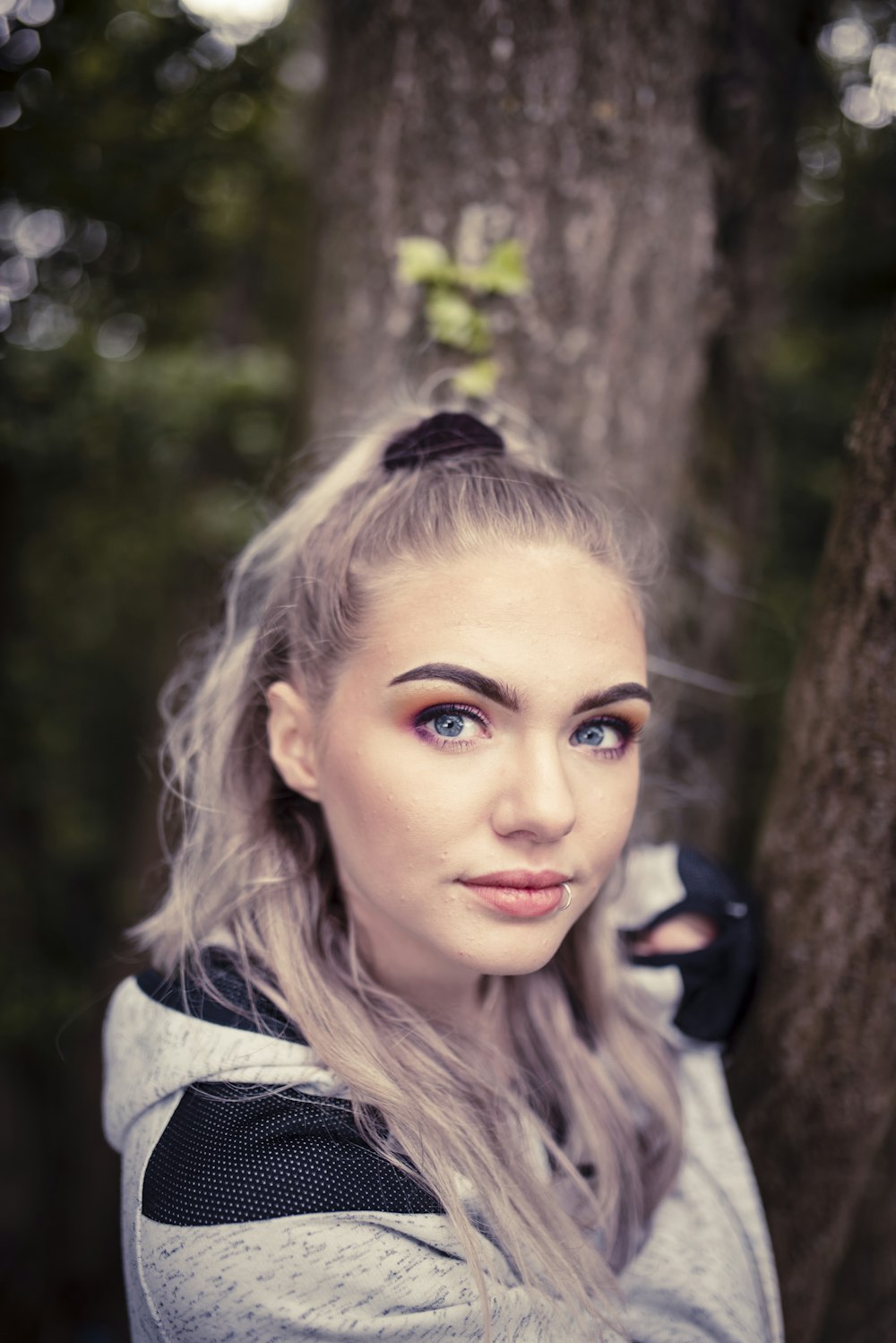 woman in grey shirt standing near tree during daytime