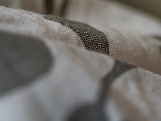 Close-up shot of a charcoal tee shirt fabric showing detailed reinforced seams and texture under stark lighting.