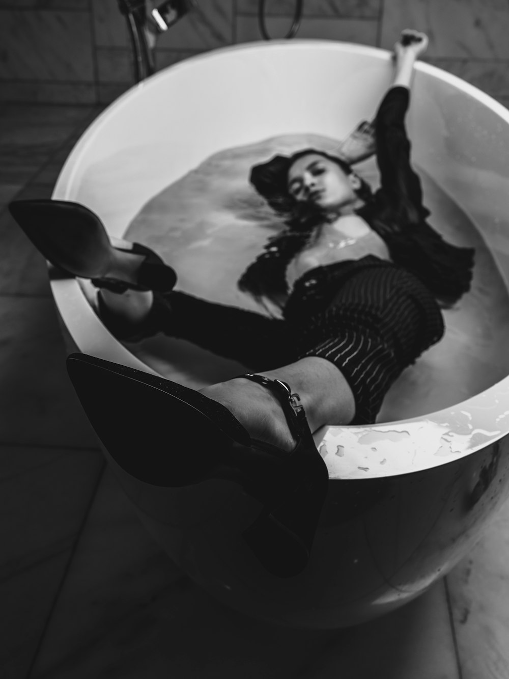 woman in black and white stripe dress lying on white ceramic bathtub