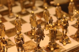 A close-up of intricately designed chess pieces with a focus on golden figures representing royalty and knights. The chessboard is elegant, with detailed craftsmanship on the pieces, highlighting a sense of luxury and historical significance.