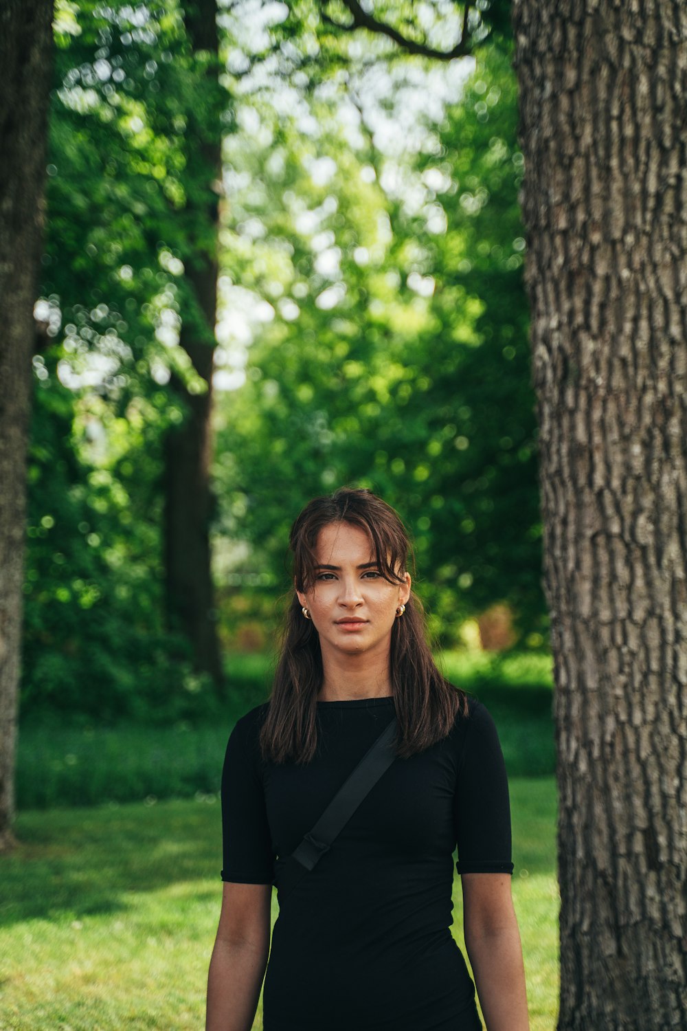 woman in black long sleeve shirt standing beside tree during daytime