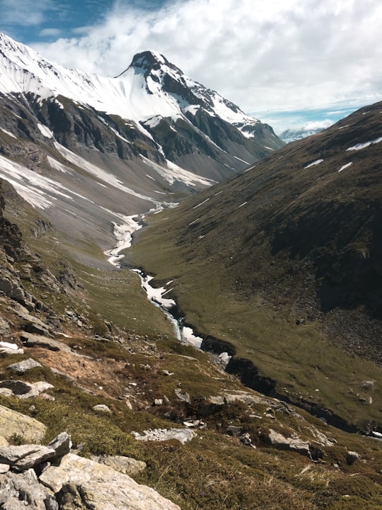 green and brown mountains under white clouds during daytime in Vanoise National Park France