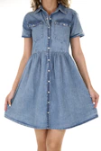 A casual denim shirt dress styled with sandals on a city street on a sunny afternoon.